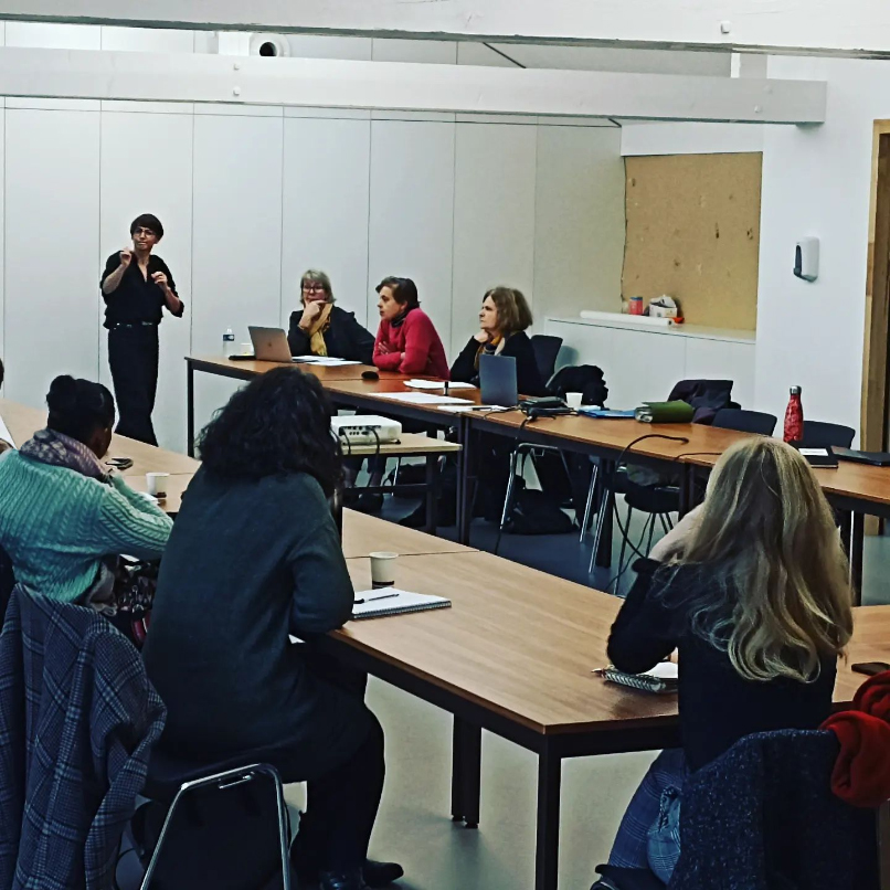 Photo en salle de réunion avec Émilie BOUGOUIN expliquant les points essentiels de la formation, debout, face aux participantes.