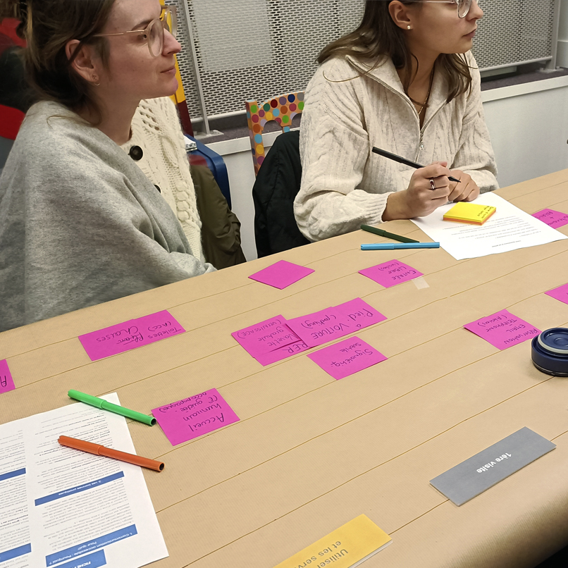 Gros plan sur la table et les post it d'un groupe de 2 participantes.