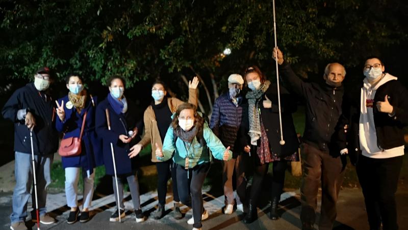 Photo en extérieur de nuit, d'un groupe masqué regardant l'objectif et levant au ciel les cannes et les pouces